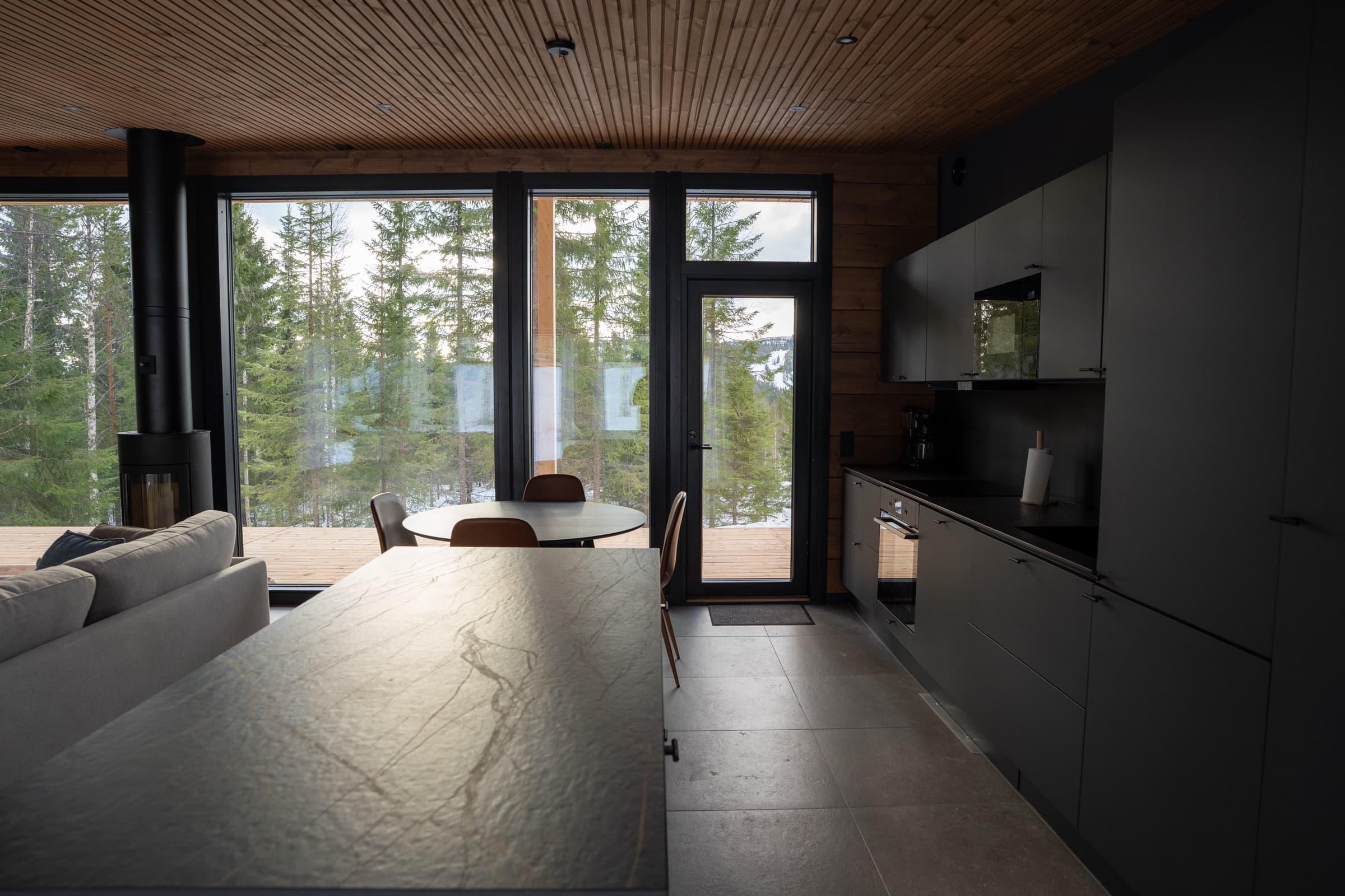 Villa Rekin olohuone ja keittiö, isot ikkunat metsään